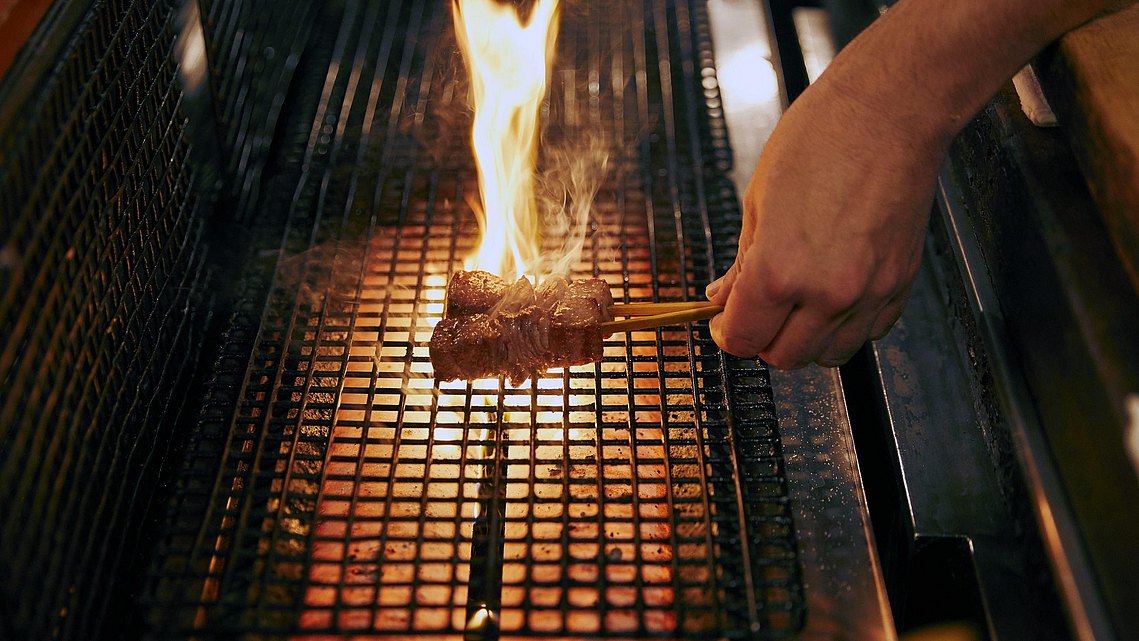 Zwei Fleischspieße werden über offener Flamme gegrillt